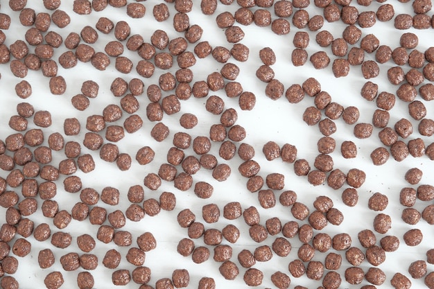 Boules de maïs au chocolat éparpillées sur un fond blanc. Vue de dessus. Copie, espace vide pour le texte