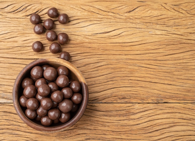 Boules maltées au chocolat dans un bol sur une table en bois avec espace de copie