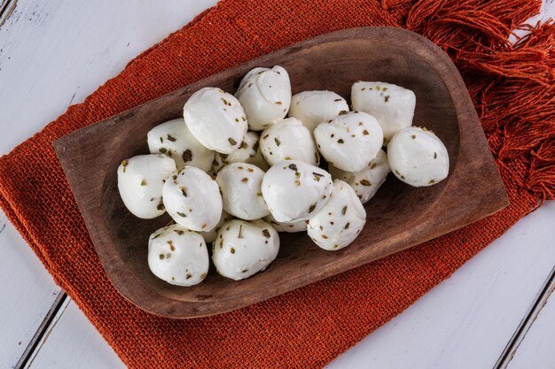 boules de mozzarella de bufflonne saupoudrées d'origan sur un plateau en bois