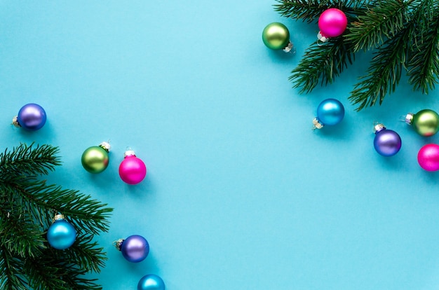 Boules multicolores avec des branches de sapin sur une surface bleue