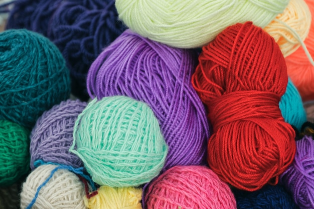 Boules multicolores de fil de laine pour tricoter, gros plan, arrière-plan