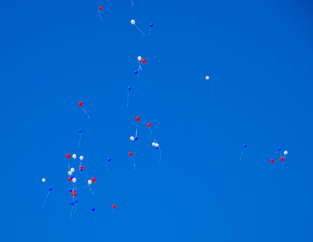 Photo des boules multicolores remplies d'hélium volent dans le ciel bleu