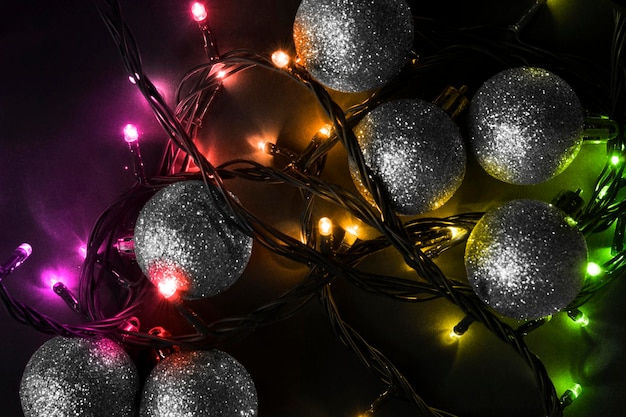 Boules de noël argentées et guirlandes de lumières led colorées dans l'obscurité