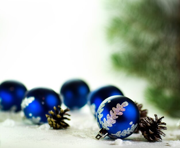 Boules de Noël bleu sur fond blanc avec des pommes de sapin