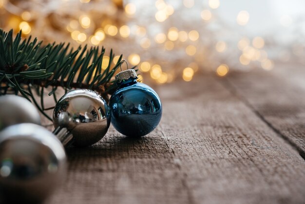 Boules de Noël bleues et argentées sur fond de bois avec bokeh de lumières de Noël