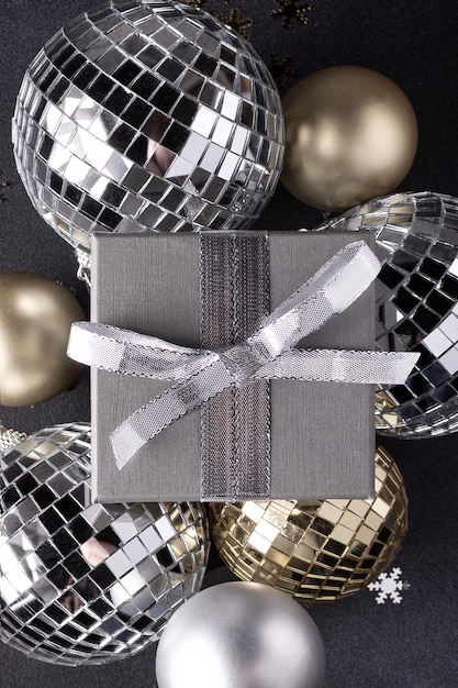 Boules de Noël en boîte cadeau de couleur or et argent sur fond noir décor de vacances de Noël