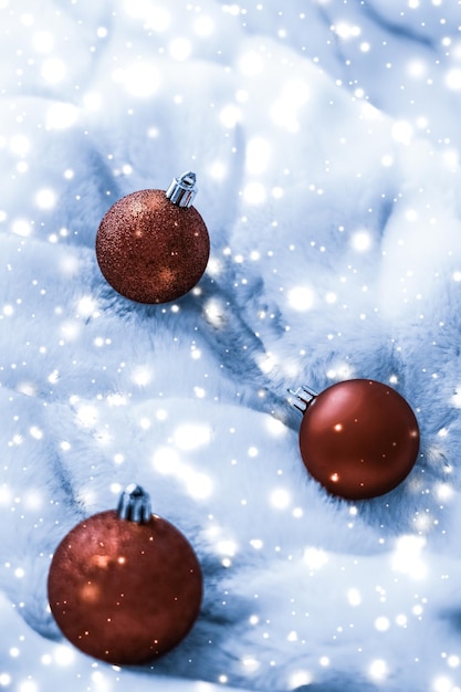 Boules de Noël en bronze sur fourrure pelucheuse bleue avec fond de conception de vacances d'hiver de luxe scintillant de neige brillante