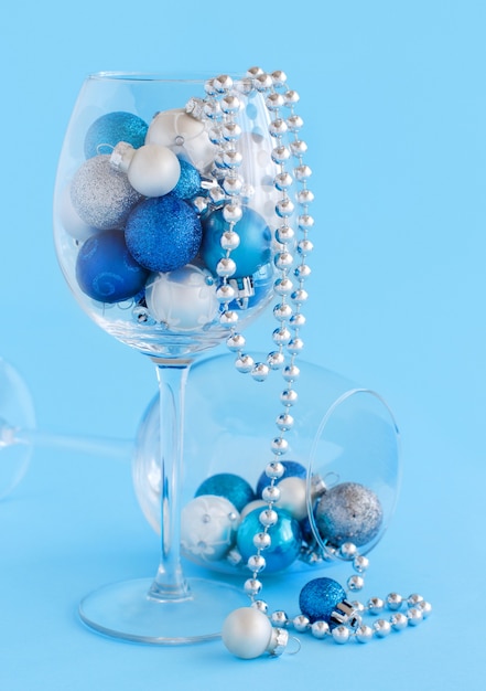 Boules de Noël dans un verre à vin sur fond bleu clair