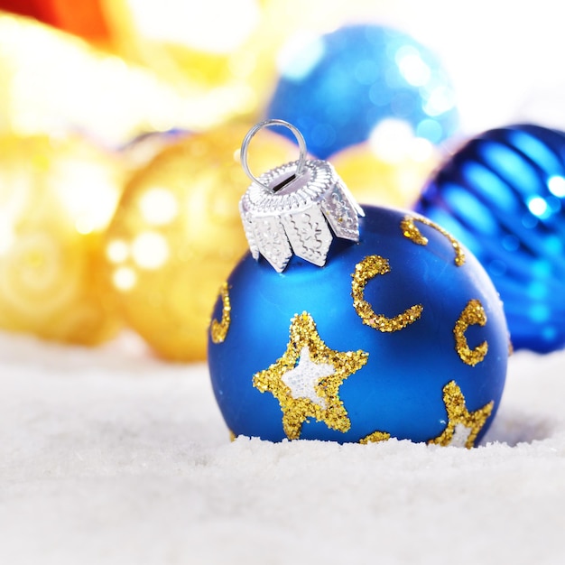 Boules de Noël dorées et bleues dans la neige en gros plan