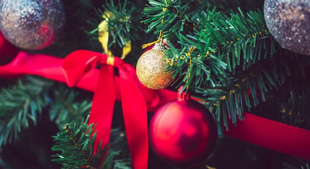 Des boules de Noël dorées et des boules rouges avec des rubans rouges ornent le fond de Noël du sapin de Noël