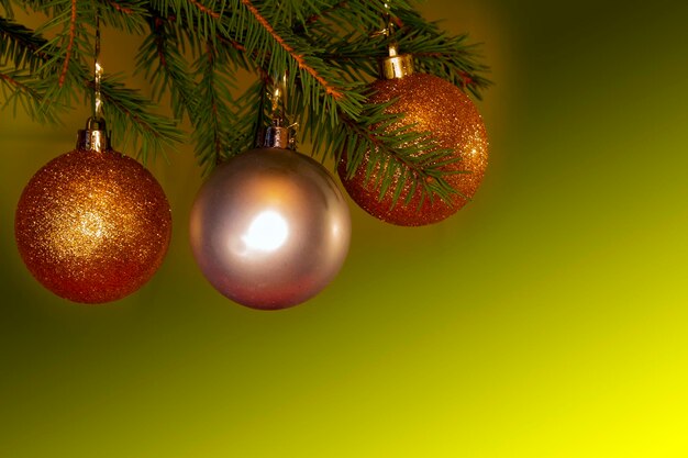 Photo des boules de noël dorées sont accrochées à un sapin de noël sur fond vert.