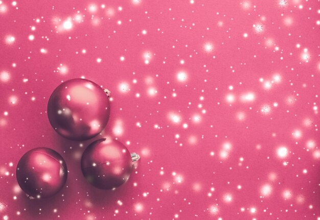 Photo boules de noël sur fond rose avec carte de vacances d'hiver de luxe scintillant de neige