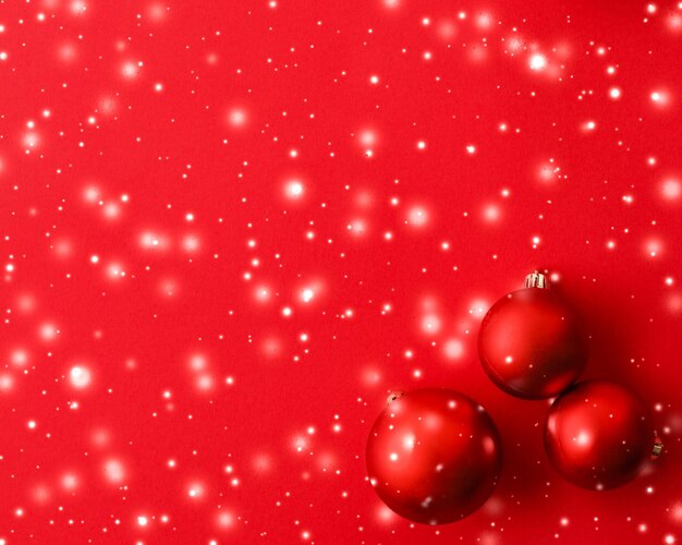 Boules de Noël sur fond rouge avec carte de vacances d'hiver de luxe scintillant de neige