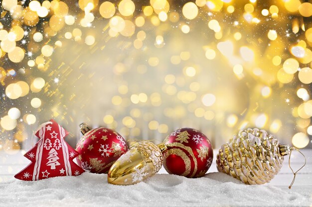 Boules de Noël lumineuses sur la neige sur fond doré avec bokeh et chutes de neige. Joyeux Noel et bonne année
