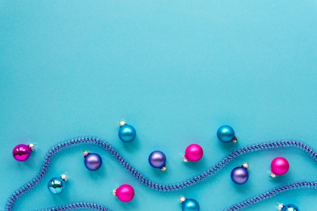 Boules de Noël multicolores et guirlandes bleues sur une surface bleue