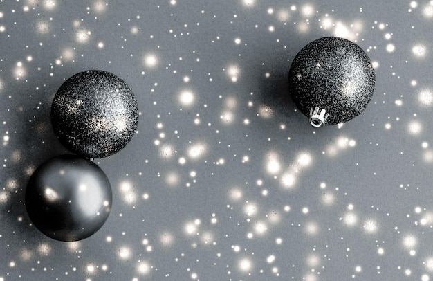 Photo boules de noël noires avec des paillettes de neige brillent carte de vacances d'hiver de marque de luxe