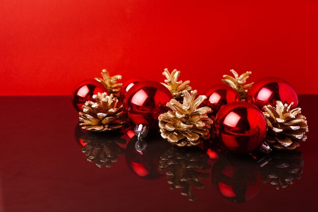 Boules de Noël rouges et cônes peints en or sur fond rouge