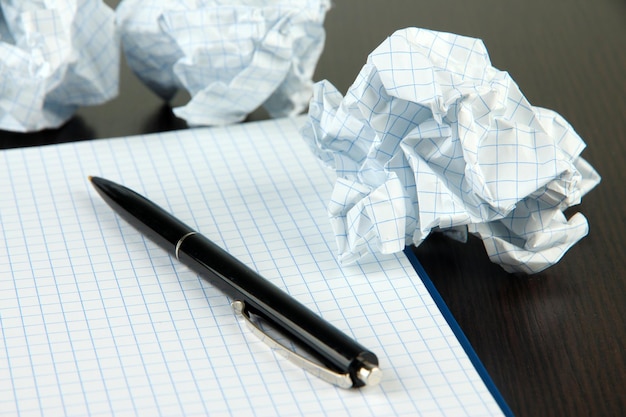 Boules de papier froissé avec carnet et stylo sur fond de bois