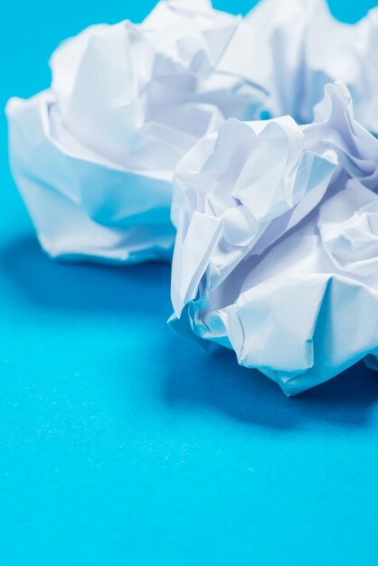 Photo boules de papier froissé de couleur blanche sur le fond bleu