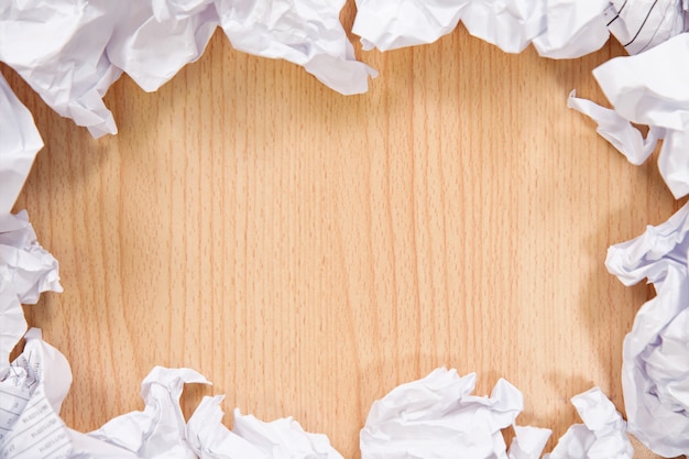 Boules de papier froissé sur fond en bois.