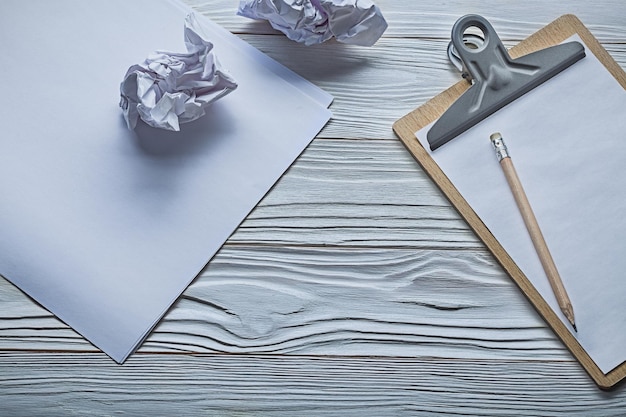 Boules de papier froissé et petit presse-papiers avec crayon sur des planches en bois blanc vintage