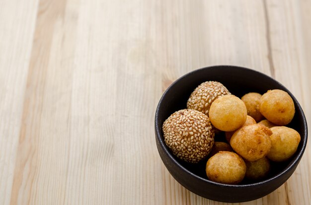 Boules de patates douces frites dans un bol noir sur une table en bois