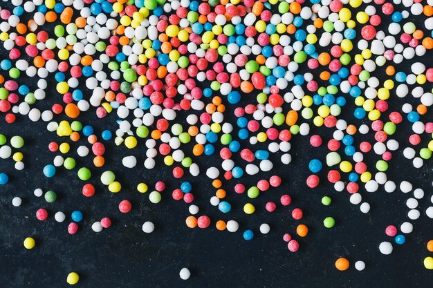 Boules de sucre colorées saupoudrées sur la vue de dessus de fond métallique grunge foncé