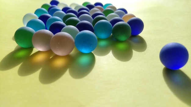 Boules de verre dépoli bleu et vert sur une surface jaune Partiellement défocalisé Un jeu tactile ou un élément de décor d'appartement Un contre tous les autres