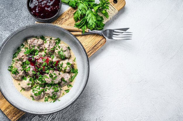 Boulettes de bœuf haché avec sauce à la crème sur une assiette. Fond en bois blanc