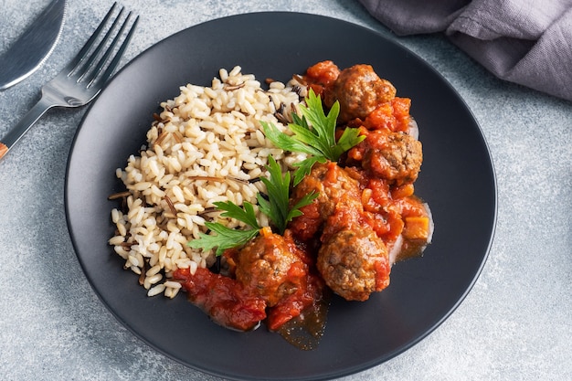 Boulettes de boeuf et riz brun sur une assiette.