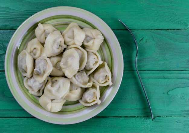 Boulettes bouillies sur une assiette sur un fond de bois vert