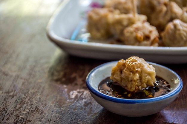 Boulettes cuites à la vapeur chinois (Dim Sum) avec de la sauce est une nourriture chinoise sur la table en bois