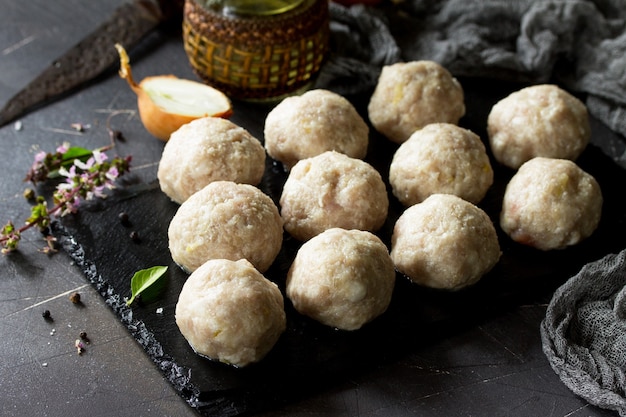 Boulettes de dinde faites maison crues sur tableau noir en ardoise