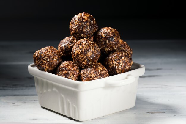 Boulettes d'énergie végétaliennes faites maison avec des flocons d'avoine, des noix, des dattes et du sésame