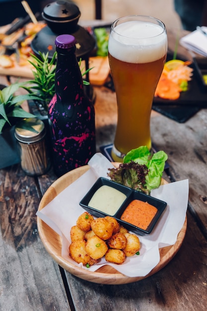 Photo boulettes de fromage mozzarella frites servies avec mayonnaise et mille îles et un verre de be