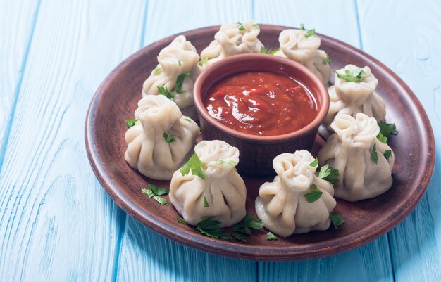 Des boulettes géorgiennes khinkali avec sauce tomate et persil