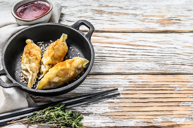 Boulettes de gyoza japonaises frites dans une casserole. Espace en bois blanc. Vue de dessus. Espace copie