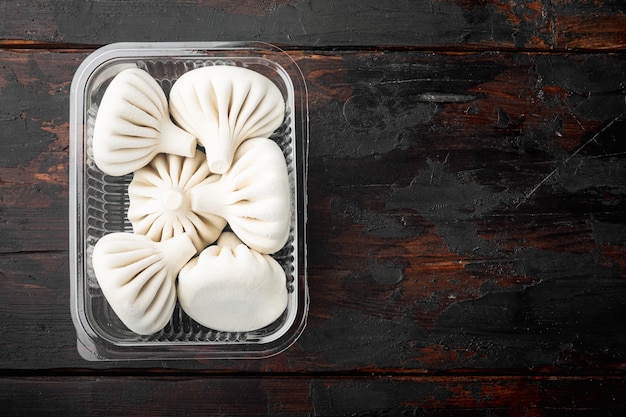 Boulettes de Manti ou manty, ensemble de plats asiatiques populaires, dans un plateau en plastique, sur une vieille table en bois foncé