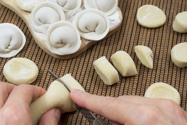 Boulettes non cuites. Les mains coupent la pâte en morceaux