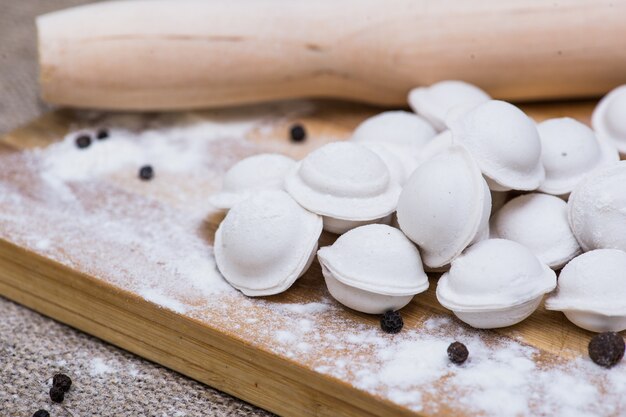 Boulettes non cuites Pelmeni. Plat russe traditionnel. Contexte de pelmeni disposé sur une planche à découper avec de la farine