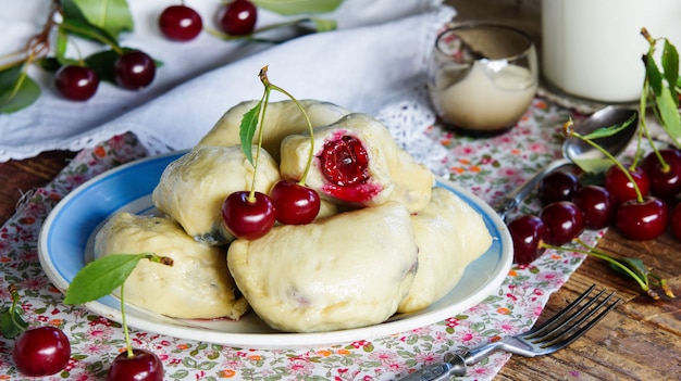 boulettes de pâte avec des cerises sur une table en bois bleu foncé