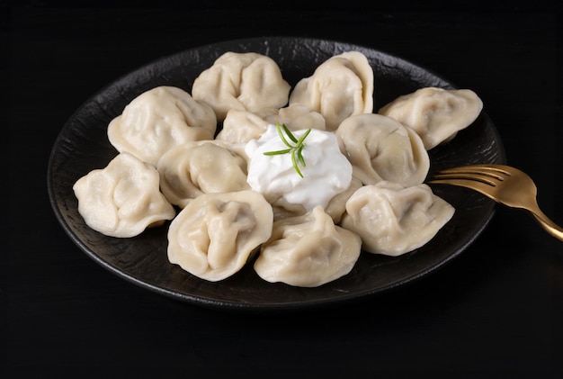 Des boulettes de ravioli pelmeni russes traditionnelles avec de la viande sur fond noir Vue supérieure