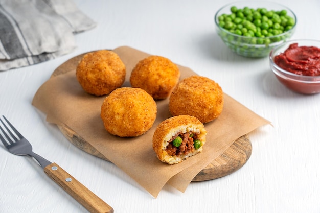 Boulettes de riz de cuisine italienne Arancini farcies de hachis et de pois verts enrobés de chapelure