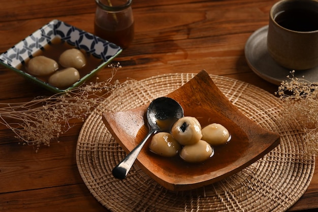 Boulettes de riz sucrées avec soupe de gingembre sucré servies dans une assiette en bois.