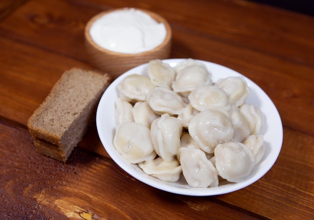 Boulettes russes traditionnelles avec de la crème sure sur un gros plan de fond en bois