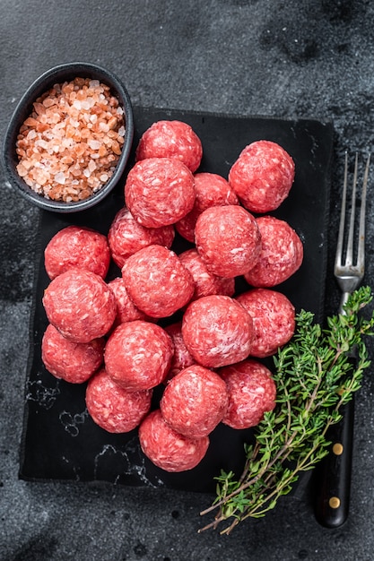 Boulettes de viande crue de bœuf haché et de viande de porc au thym. Fond en bois. Vue de dessus.