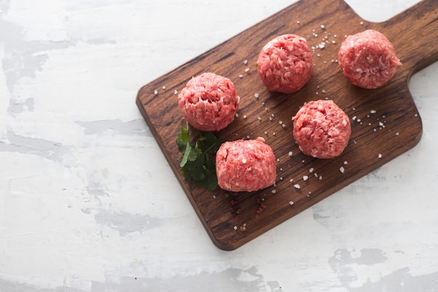 Boulettes de viande crues avec du poivre et du sel dans une boîte en plastique