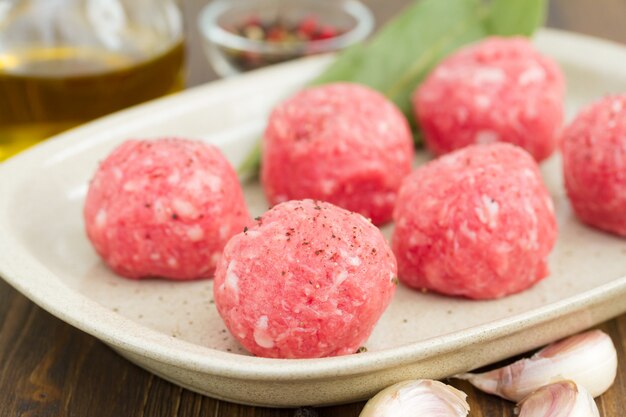 Boulettes de viande crues sur le plat sur une surface en bois