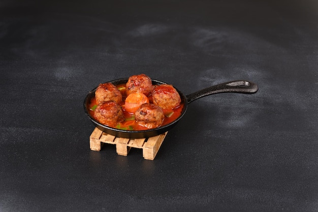 Boulettes de viande cuites à la sauce tomate dans une casserole sur fond sombre