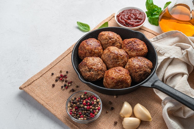 Boulettes de viande dans une poêle à frire sur fond gris. Vue latérale, copiez l'espace.